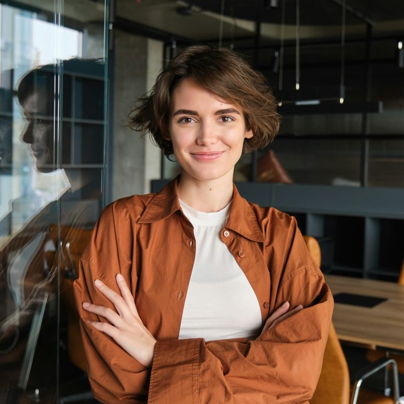 Portrait of young confident woman, start-up manager in office, posing with confidence, looking self